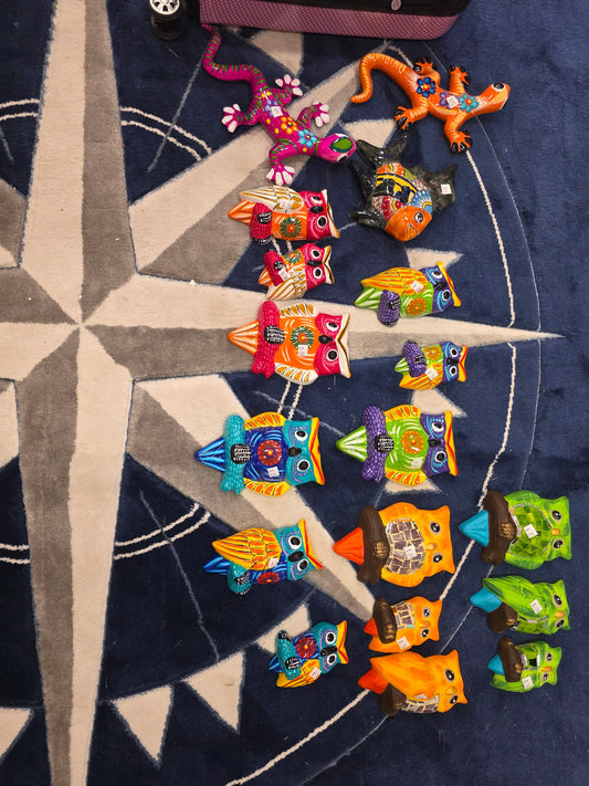 Colorful ceramic owl figures in several sizes, two lizards, and a fish arranged on a navy compass-patterned rug