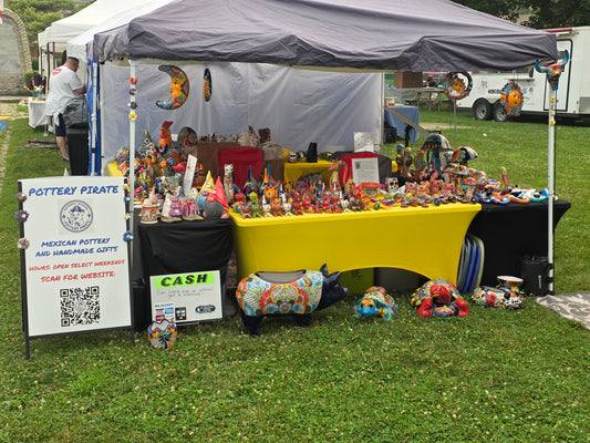 vendor booth featuring talavera ceramics for sale on a yellow table with a grey tent