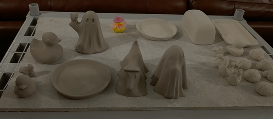 yellow duck in a pink hat on a shelf with pottery greenware ghosts ladybugs and ducks