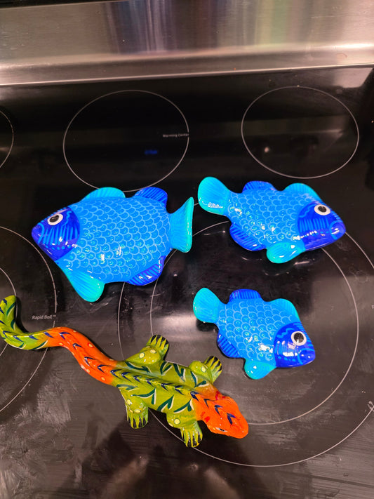 blue fish with a green and orange lizard on a stovetop