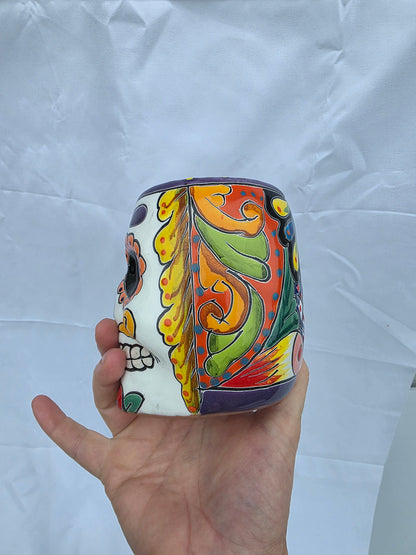 Colorful ceramic container held by a hand on a white background