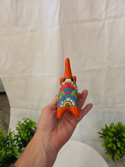 Hand holding a colorful ceramic CAT with a decorative design on a white surface.