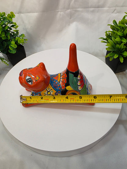Decorative cat  with a measuring tape on a white surface with plants.