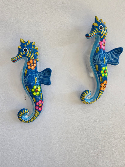 Pair of 10-inch hand-painted blue Mexican Talavera ceramic seahorse wall art pieces hanging on a white wall.