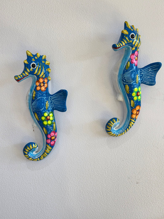 Pair of 10-inch hand-painted blue Mexican Talavera ceramic seahorse wall art pieces hanging on a white wall.