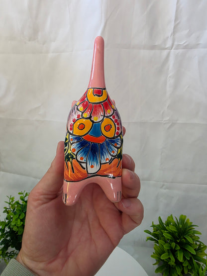 Hand holding a colorful ceramic cat butt with floral design on a white background