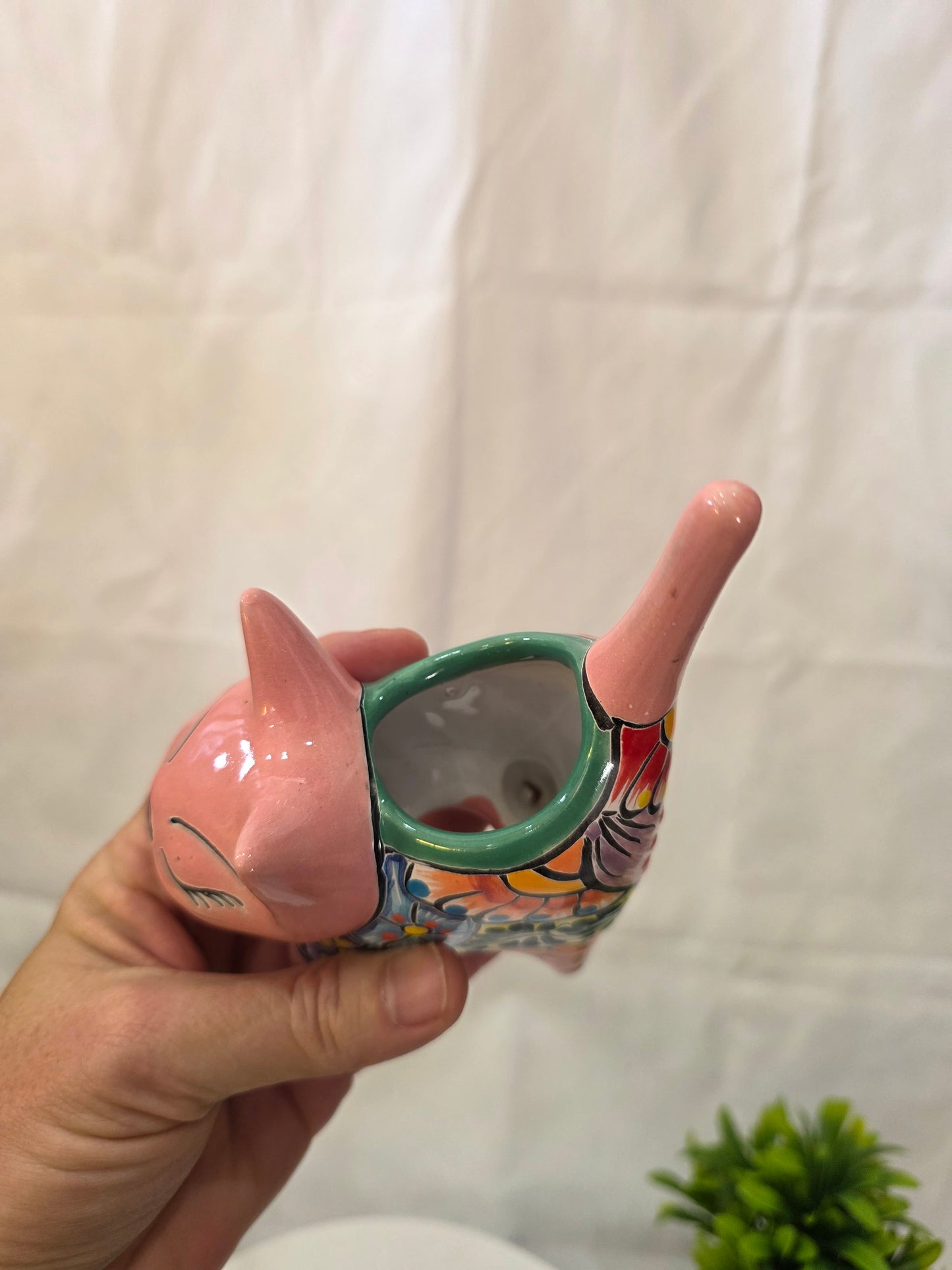 Decorative ceramic cat planter with colorful design held by a hand on a white background