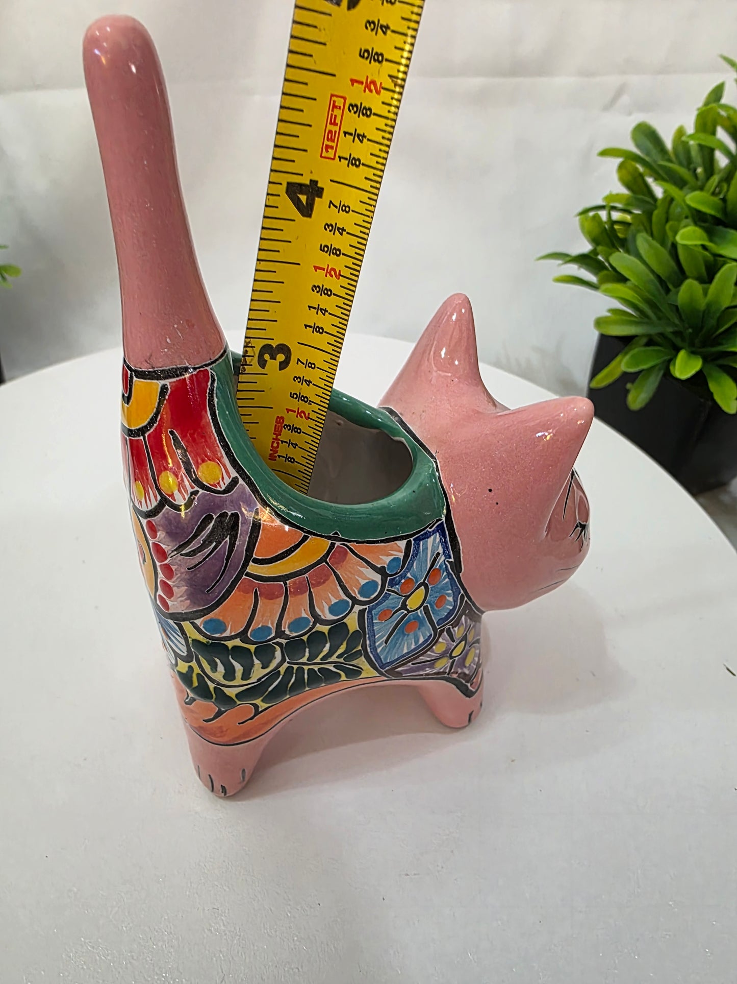 Decorative ceramic cat planter with colorful patterns and a measuring tape for scale on a white background.